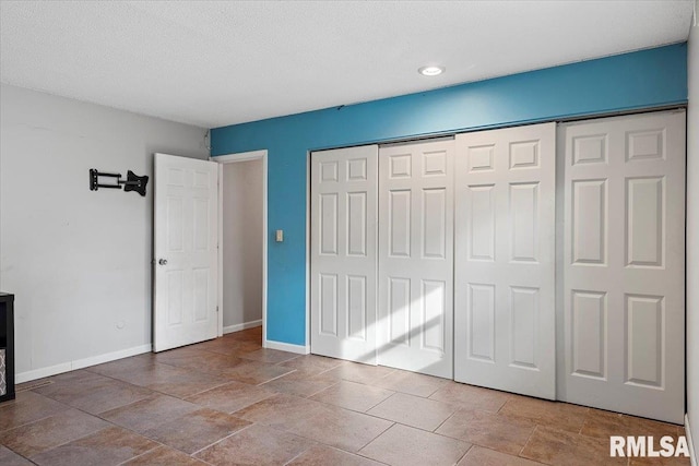 unfurnished bedroom featuring stone finish floor, a textured ceiling, baseboards, and a closet