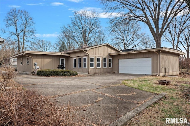 view of front facade with aphalt driveway, a chimney, and an attached garage