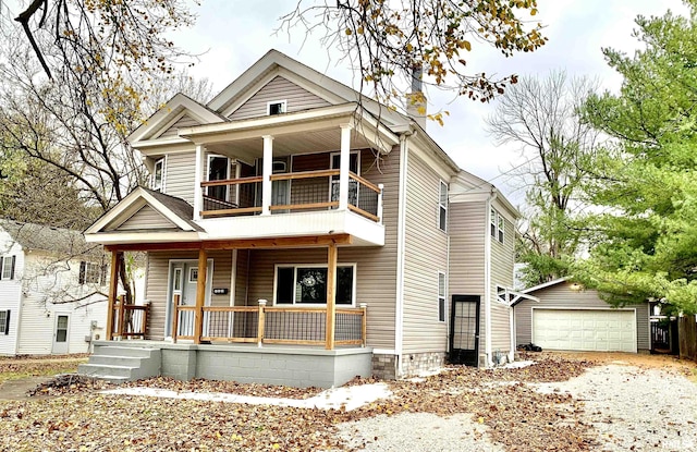 view of front of house featuring a porch, an outbuilding, a detached garage, and a balcony