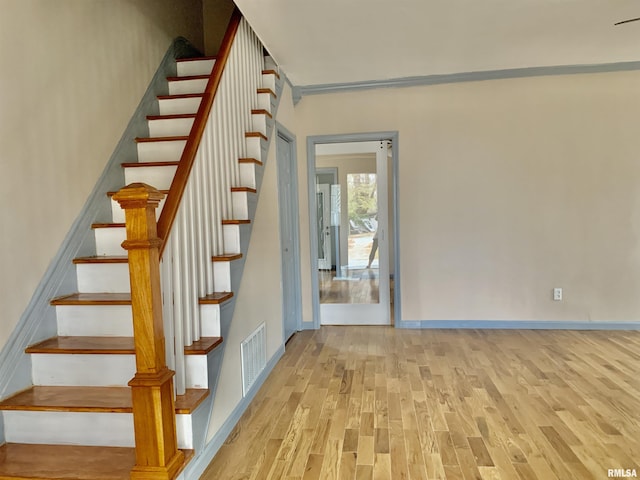 staircase with wood finished floors, visible vents, and baseboards