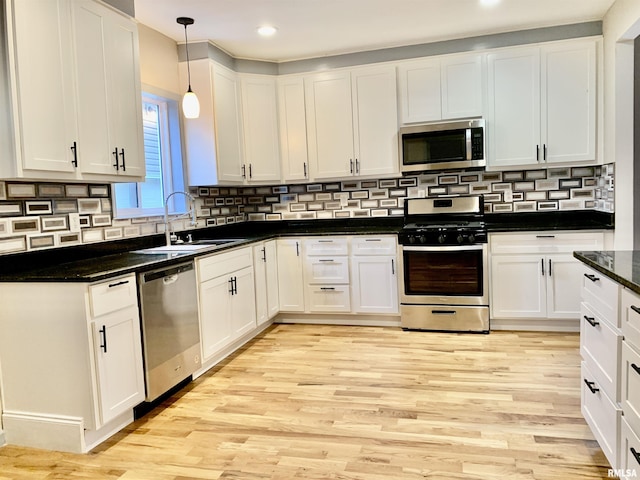 kitchen featuring appliances with stainless steel finishes, light wood-type flooring, white cabinetry, and a sink