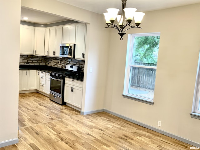 kitchen featuring dark countertops, white cabinets, stainless steel appliances, and decorative backsplash