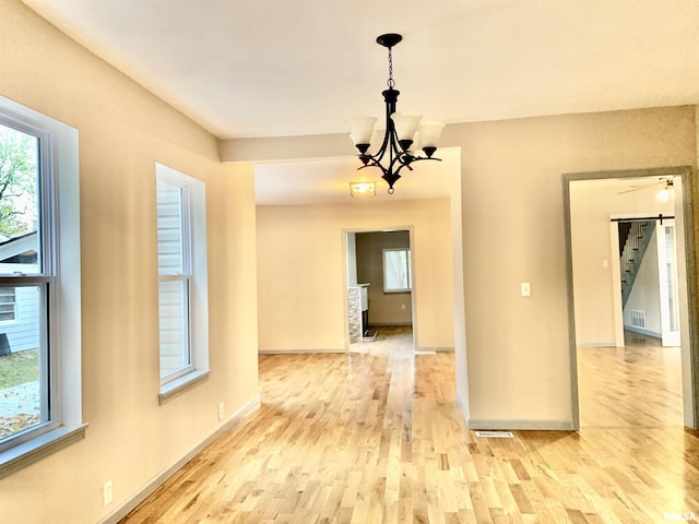 interior space with light wood-style floors, baseboards, a chandelier, and a wealth of natural light