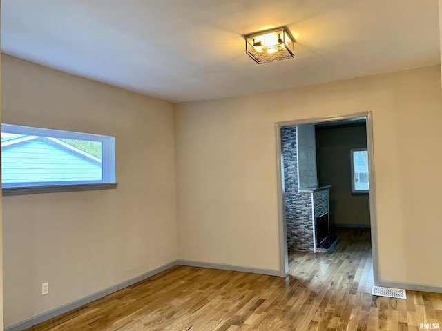 spare room featuring baseboards, a fireplace, and light wood-style floors