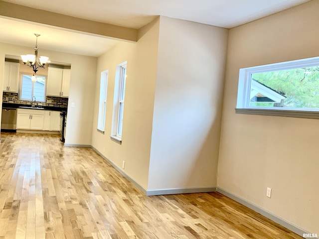 interior space with white cabinets, decorative backsplash, dishwasher, dark countertops, and light wood-style floors