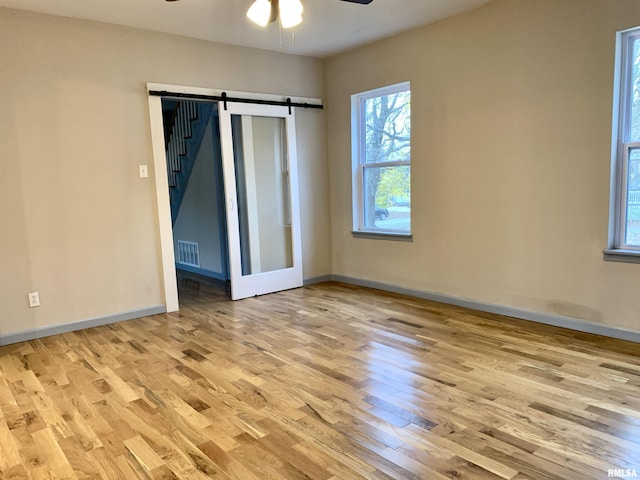 unfurnished room featuring ceiling fan, wood finished floors, visible vents, and baseboards