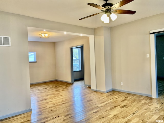 empty room with wood finished floors, visible vents, and baseboards