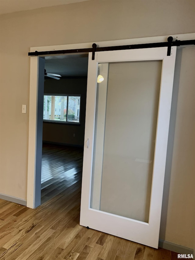 interior space with a barn door, baseboards, and wood finished floors