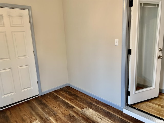 empty room with dark wood-style flooring and baseboards