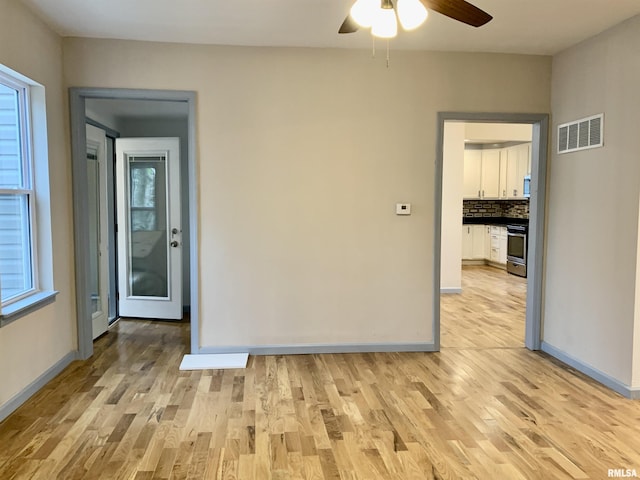 unfurnished room with light wood-type flooring, baseboards, and visible vents