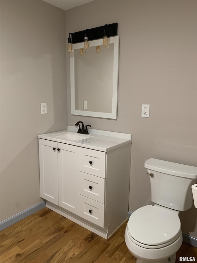 bathroom with toilet, baseboards, wood finished floors, and vanity