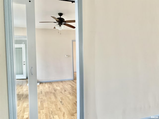 spare room with light wood-type flooring, ceiling fan, and baseboards