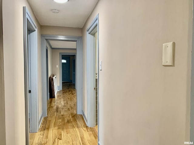 corridor featuring light wood-style flooring and baseboards