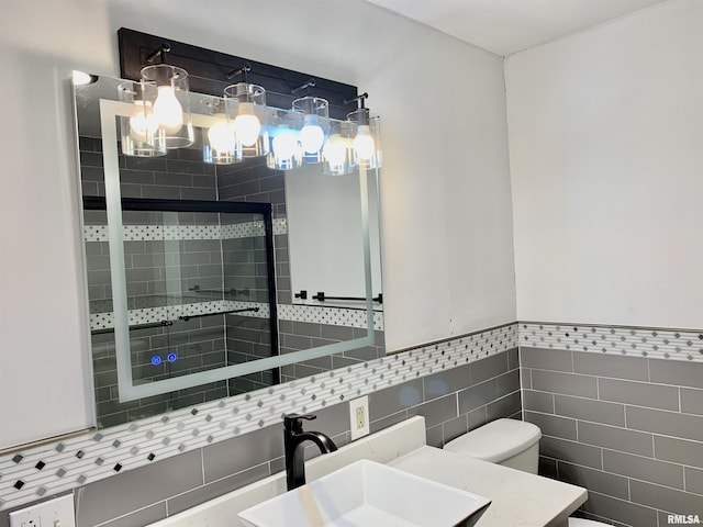 bathroom featuring a wainscoted wall, tile walls, toilet, a shower stall, and vanity