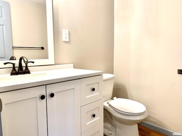 bathroom featuring baseboards, vanity, toilet, and wood finished floors