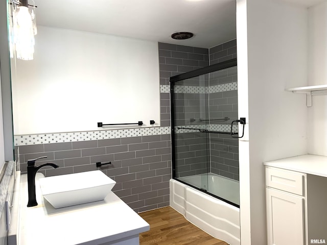 bathroom featuring enclosed tub / shower combo, tile walls, vanity, and wood finished floors