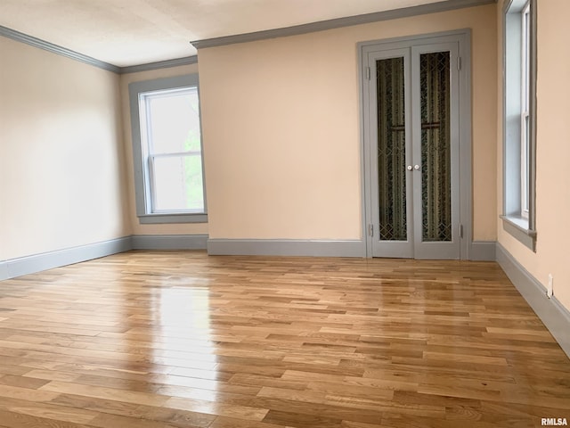 unfurnished room with light wood finished floors, french doors, baseboards, and crown molding