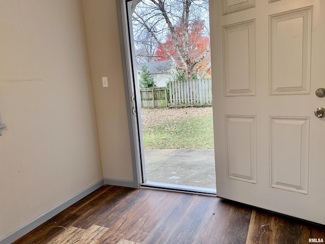 doorway with dark wood-type flooring and baseboards