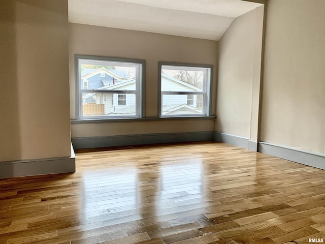 spare room with lofted ceiling, baseboards, and wood finished floors