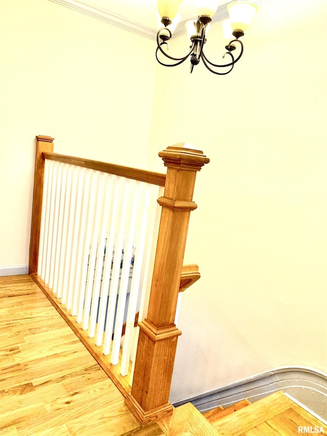 staircase featuring a chandelier, ornamental molding, baseboards, and wood finished floors