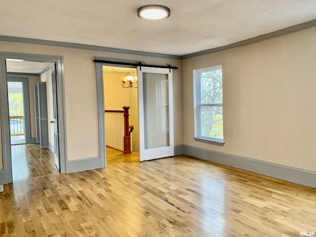 empty room featuring ornamental molding, light wood-style flooring, and baseboards