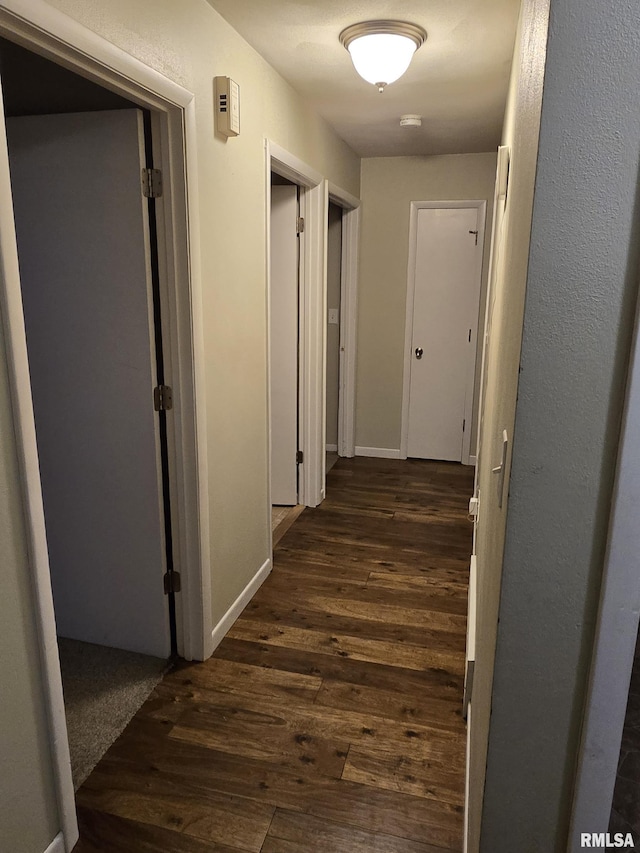 hall with dark wood-type flooring and baseboards