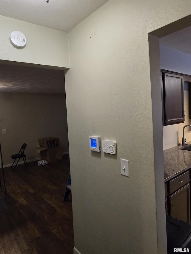 hallway featuring dark wood-type flooring, a sink, and baseboards