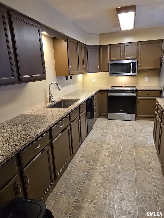 kitchen with appliances with stainless steel finishes, a sink, and light stone countertops