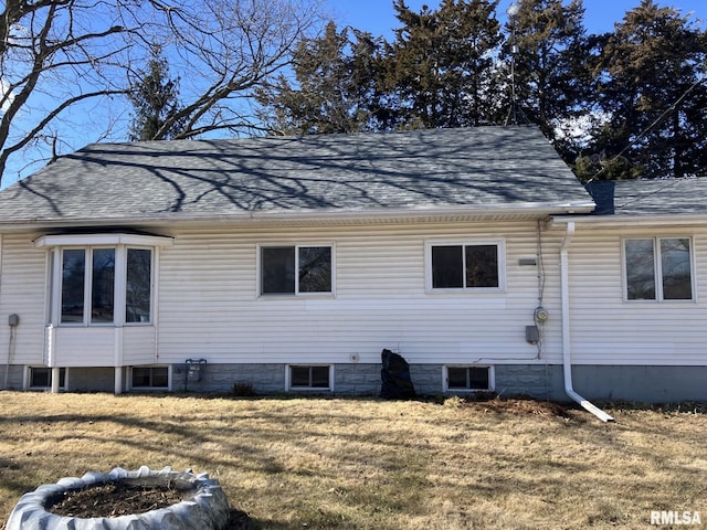 view of side of property with a shingled roof and a lawn