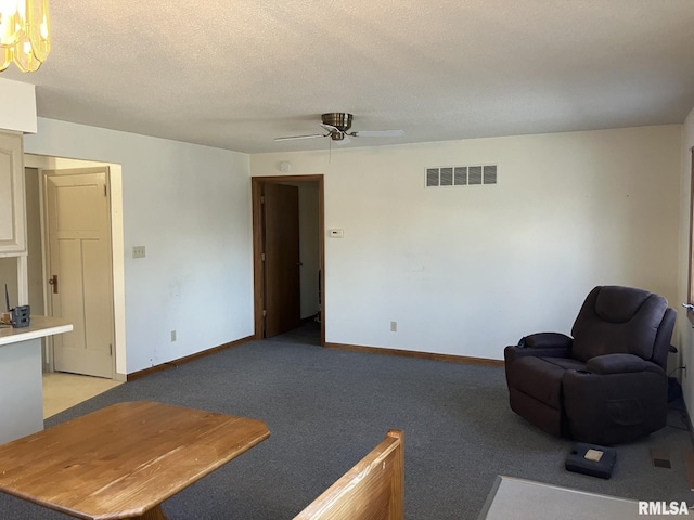 living room featuring light carpet, baseboards, visible vents, ceiling fan, and a textured ceiling