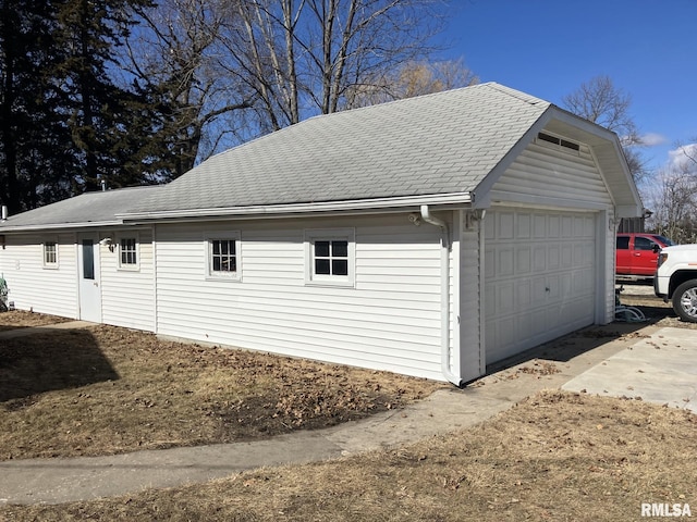 view of property exterior with a shingled roof, a detached garage, and an outbuilding