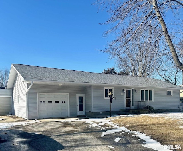 ranch-style house featuring an attached garage, a shingled roof, and aphalt driveway