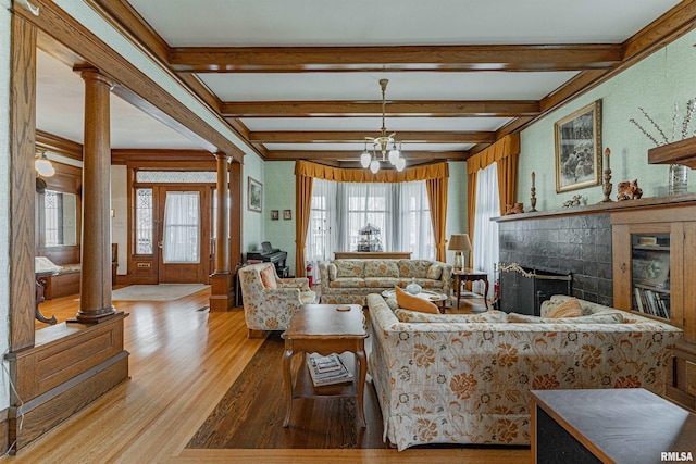 living room featuring a healthy amount of sunlight, ornate columns, beam ceiling, and wood finished floors