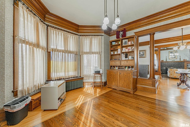 interior space featuring crown molding, wood finished floors, a fireplace, and wallpapered walls