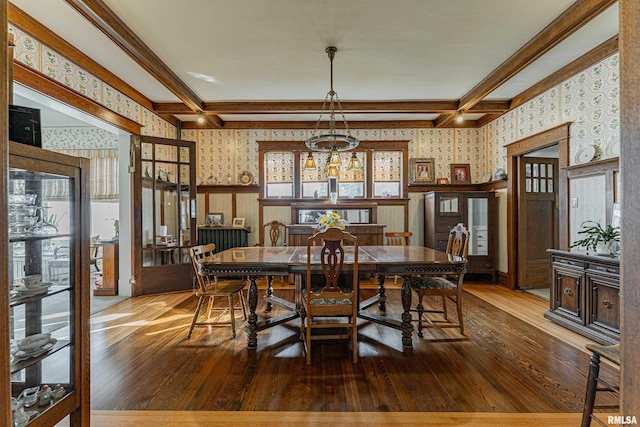 dining room featuring a wainscoted wall, hardwood / wood-style floors, beamed ceiling, and wallpapered walls