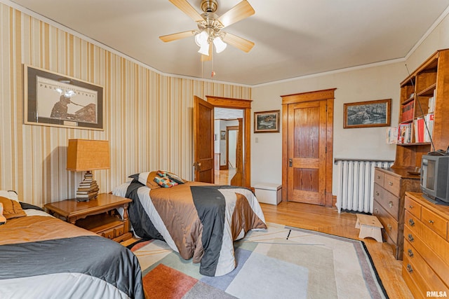 bedroom featuring ornamental molding, radiator heating unit, light wood-style flooring, and a ceiling fan