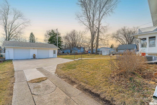 yard at dusk featuring a garage, cooling unit, and an outdoor structure