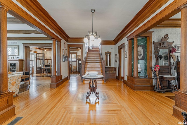 entryway with crown molding, decorative columns, visible vents, an inviting chandelier, and stairs