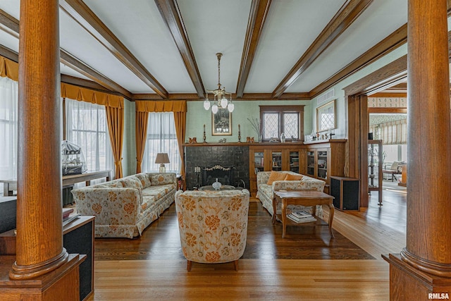 living area featuring a fireplace, wood finished floors, and ornate columns