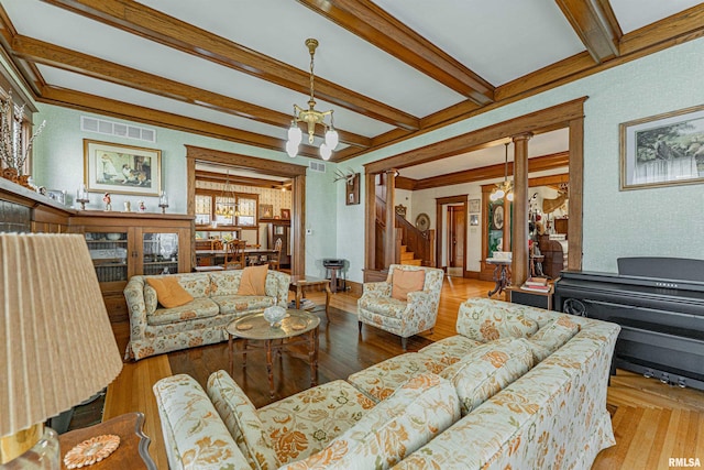 living area featuring a chandelier, visible vents, beam ceiling, decorative columns, and wallpapered walls