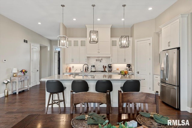 kitchen with a sink, stainless steel fridge, and white cabinets