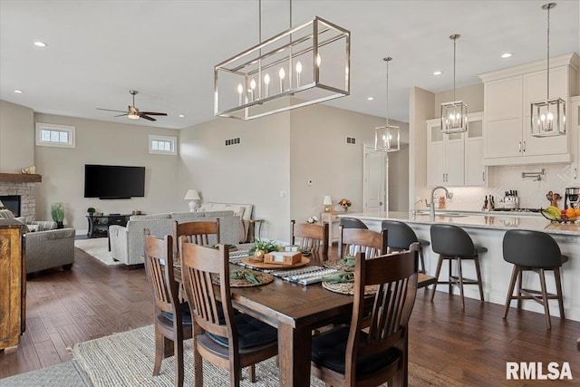 dining room featuring visible vents, ceiling fan, dark wood-type flooring, a fireplace, and recessed lighting