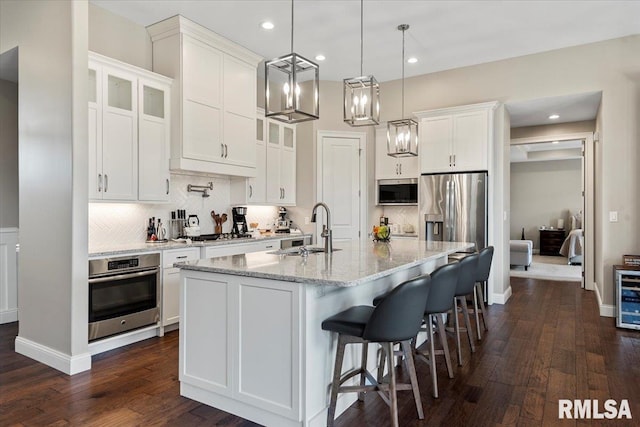 kitchen featuring stainless steel appliances, white cabinetry, a sink, and backsplash