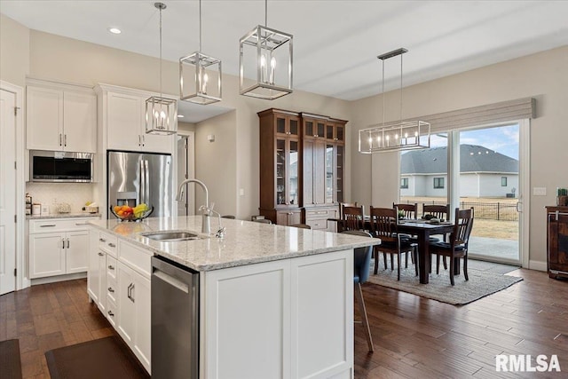 kitchen with dark wood-style floors, appliances with stainless steel finishes, white cabinets, and a sink