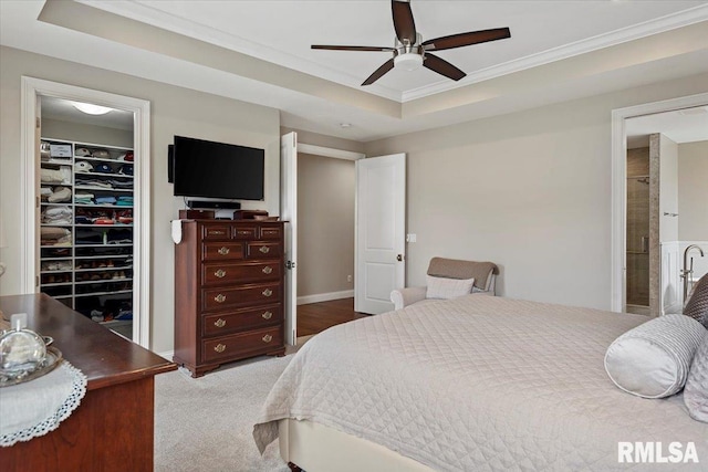 bedroom with ornamental molding, a closet, a raised ceiling, and a walk in closet