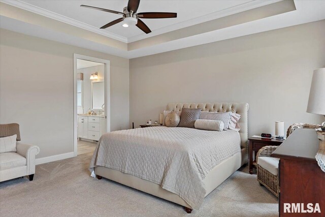 bedroom featuring a raised ceiling, light colored carpet, ensuite bathroom, ornamental molding, and baseboards