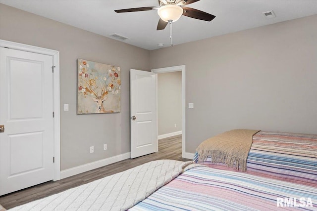 bedroom with baseboards, visible vents, ceiling fan, and wood finished floors