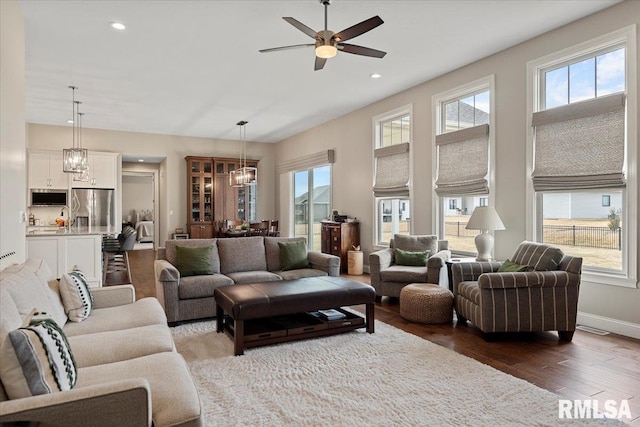 living room with ceiling fan with notable chandelier, recessed lighting, wood finished floors, and baseboards