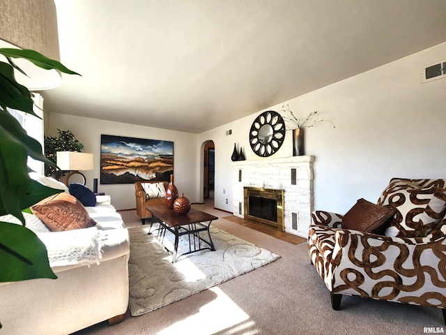 carpeted living room with arched walkways, a fireplace, and visible vents