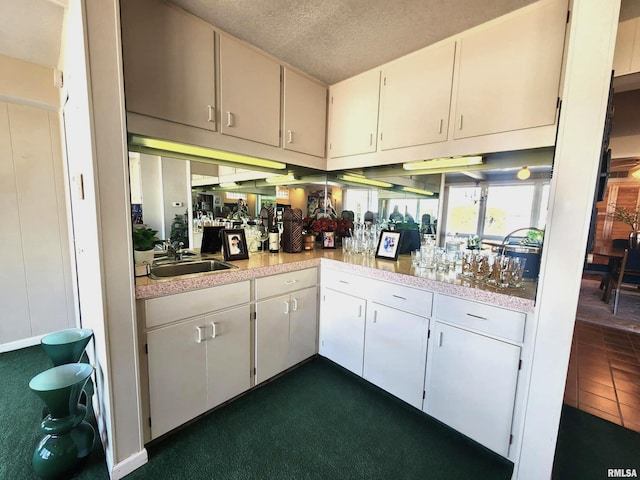 kitchen featuring a textured ceiling, light countertops, and a sink